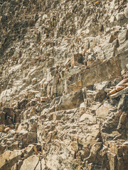 Natural background. Closeup edged shabby cliff cracks. Gray-brown stone rock texture of mountains. Vintage and faded matt style colour in tinted photo. Concept of geolog, mountaineering or hard work