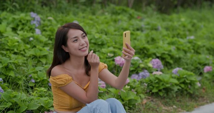 Woman take selfie on cellphone in flower garden