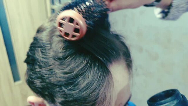 Dry a young client's hair with a brush and hair dryer in the salon scene