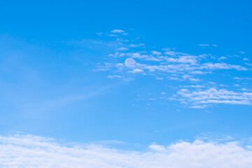 Naklejka na ściany i meble Day moon against a blue sky with Cirrus Cumulus clouds.