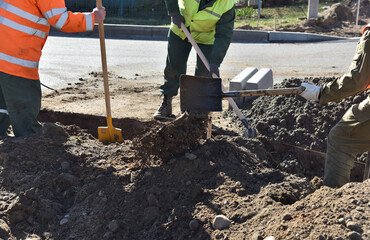 Workers dig a hole to install concrete curbs, build a road.