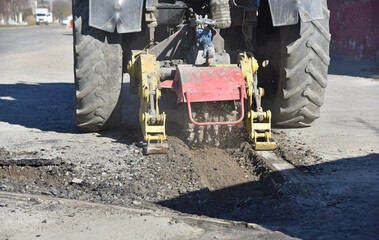 The tractor removes the top layer of asphalt. Preparing the road surface for resin filling.