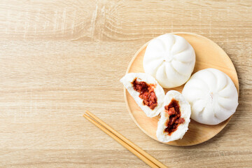 Steamed buns stuffed with red minced pork on wooden background, Asian food	
