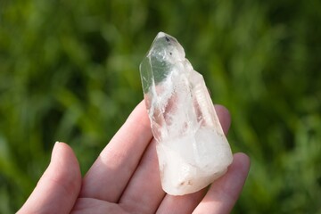White clear quartz rock crystal in female hand close up.