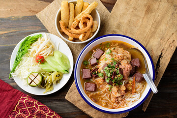 Northern Thai food (Kanom Jeen Nam Ngeaw), Rice noodles spicy soup with pork and pork blood in bowl eating with fresh vegetables and pork rind