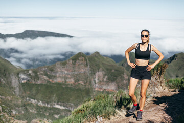 Athletic young woman in fit top and shorts does jogging and sports exercises in the mountains. Active tourism in Madeira
