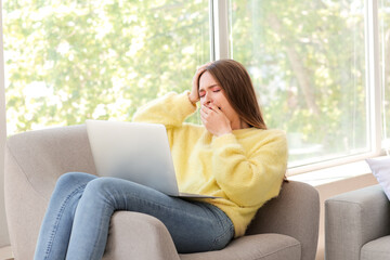 Young woman suffering from sleep deprivation with laptop at home