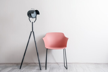 Stylish armchair with lamp near light wall