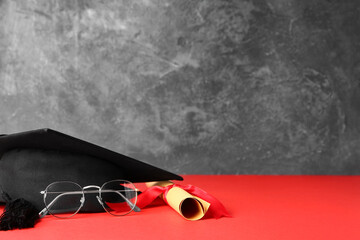 Graduation hat, glasses and diploma on table