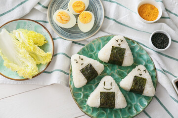 Plate with traditional Japanese onigiri and ingredients on table