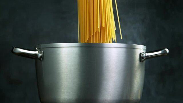 Throwing pasta spaghetti into boiled water in pot shooting with high speed cinematic camera at 1000 fps.