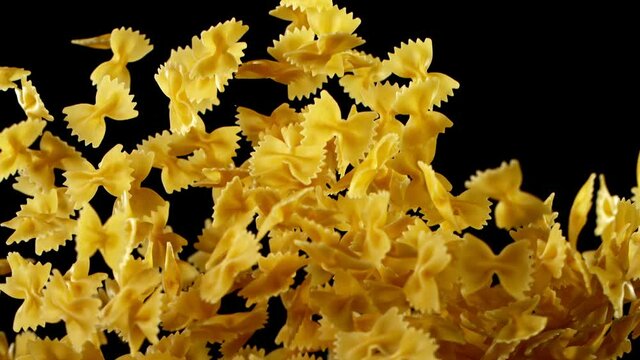 Super slow motion of flying uncooked italian pasta farfalle on black background. Filmed on high speed cinema camera, 1000 fps.