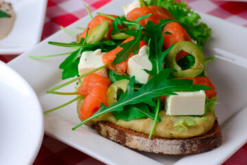 Italian traditional bruschetta with tomato basil and green olives. Served on a white plate over red plaid tablecloth.