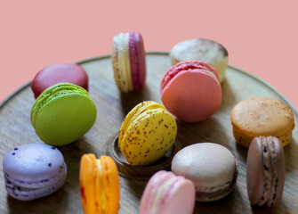 Colorful macaroon desserts on the wooden round table, close up