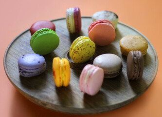 Colorful macaroon desserts on the wooden round table, close up