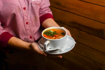Man holding a bowl of soup. Waiter serving fresh hot soup in a diner or restaurant. Healthy delicious dinner.