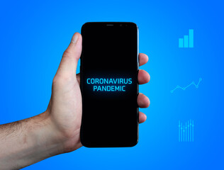 Coronavirus pandemic. Hand holds phone (cell phone). Word on display. Charts on blue background. Business