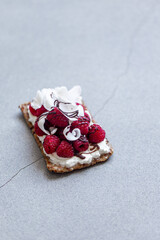 Obraz na płótnie Canvas sandwich with raspberries, cream cheese and coconut flakes on marble background with copy space