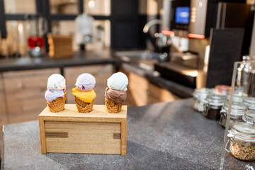 Ice cream in waffle cone with different flavors on the store counter, close-up