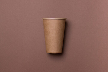 Eco-friendly cardboard cup lie on a brown color paper background. Mock-up. Close-up. The concept of ecology
