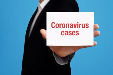 Coronavirus cases. Businessman (Man) holding a card in his hand. Text on the board presents term. Blue background. Business, Finance, Statistics, Analysis, Economy