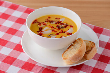 Hot and sour soup with shrimps and clams. Sea food soup with sauce served in a white bowl over light rustic wooden table