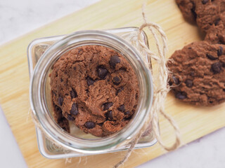 Top view homemade double chocolate chip cookies in glass bottle on wooden plate...