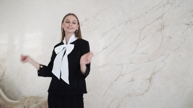 A business woman poses in a black jacket and trousers in a home interior. Sexy female model in a grey suit walks forward . 4 K