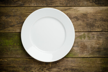 Empty white plate on wooden table close up