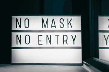 Covid-19 mask obligatory to enter stores . SIGN NO MASK NO ENTRY at storefront window. Face covering wearing mandatory when shopping outside of home. Coronavirus prevention measure.