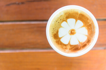 Hot coffee in hand / hot cappuccino with nice pattern in hand and wood background