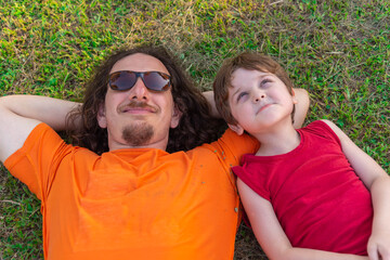 Brazilian boy lying on the grass with his uncle looking at the sky