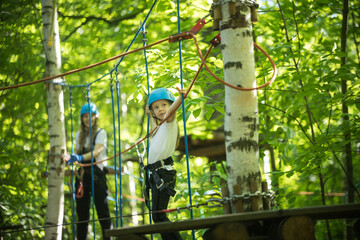 Obraz na płótnie Canvas Rope adventure in the forest - a little girl and her mother having an entertainment on the rope bridge