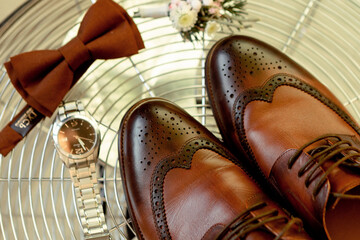 leather brown men's shoes, bow tie, watch and boutonniere