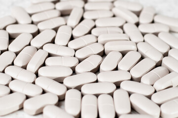 Fototapeta na wymiar White oblong tablets in the form of capsules on a light background