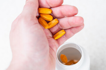 The process of throwing orange tablets into a white jar from a hand