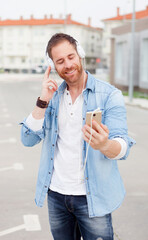 Casual guy in the street listening music with his mobile