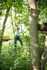 A man having a rope adventure in the forest with full insurance - sliding down using his insurance belt
