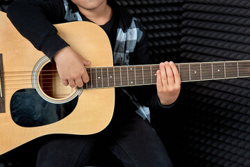 Fototapeta na wymiar Photo without a face. Cute brunette boy plays the guitar