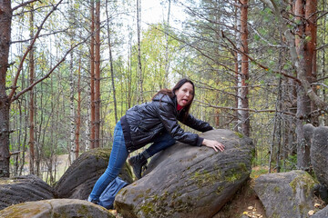 Beautiful young woman near very big stone in the forest with sprice in autumn, spring or summer