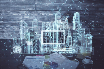 Desktop computer background in office and big town buildings hologram drawing. Double exposure. Smart city concept.
