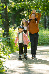 Fototapeta premium Young happy family of parents and two little kids walking in the forest