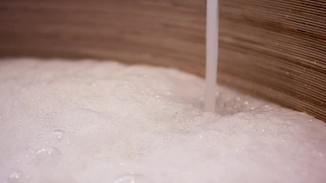 Wooden bath tub with running water and a bubble bath