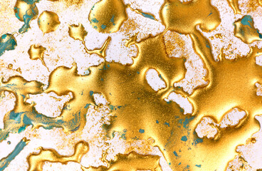 Golden ink drops on white paper background.