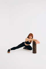 Athlete girl stretching her joints. Photo of young european girl doing exercises on white background. Sport