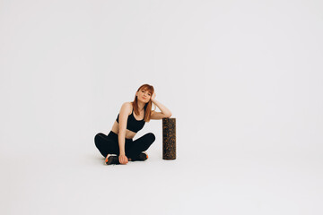 Obraz premium Athlete girl stretching her joints. Photo of young european girl doing exercises on white background. Sport