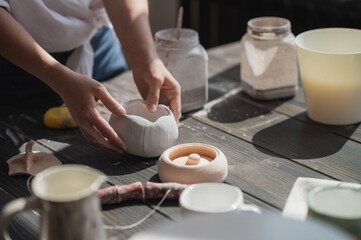 Close up of a woman making ceramic and pottery tableware at the workshop, working with clay and glaze.
