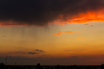 Black thunderclouds at sunset. Bright orange sunset and dark clouds. Storm sky