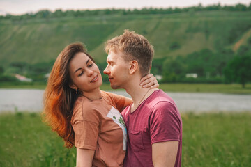 A married young happy couple a man and a woman fool around and hug against the background of a natural landscape with mountains and a lake
