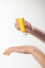 Female hands on a white background. Cream, yellow moose on the skin.